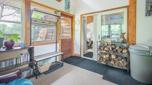 A cozy room with a wooden bench, a bookshelf, a large window, and a door leading to another room. - Lakeview cabin, 3 min walk to the beach! (Grand Marais)
