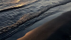 A beach at sunset with the sun reflecting on the water. - Lakeview cabin, 3 min walk to the beach! (Grand Marais)