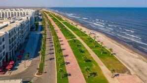 Een kusthotel met een lange promenade, palmbomen en uitzicht op de oceaan.