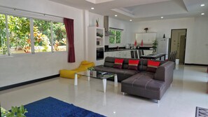 Una sala de estar moderna con un sofá, un sillón amarillo, una mesa de centro de vidrio y una alfombra azul.
