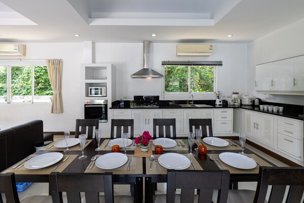 A modern kitchen with white cabinets, a central island, and a dining area set for six.