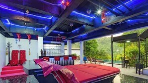 A modern hotel room with a large bed, a bar area, and a view of lush greenery. - Villa Nap Dau Crown Private Pool Villa Phuket (Tambon Chalong)