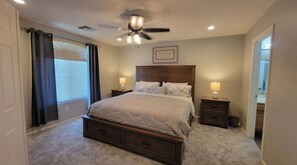 A bedroom with a bed, two bedside tables, a ceiling fan, and a window with curtains. - Charming 4 bed / 3 bath house, full amenities! (Sun City)