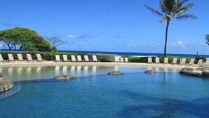 A clear blue pool with lounge chairs and a palm tree. - Ocean view room, Beachfront Kauai Beach Resort, Jacuzzis, 4 pools, restaurants (Lihue)