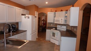 A compact kitchen with white cabinetry, a built-in oven, and a stainless steel sink.
