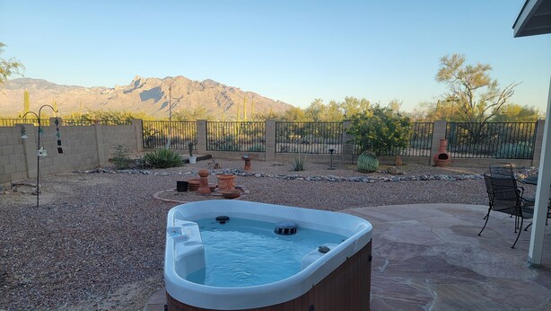 A hot tub in a backyard with a view of mountains.