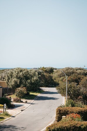 A residential street with a curved road, surrounded by dense shrubbery and trees. - Banksia by the Bay (Collingwood Park)