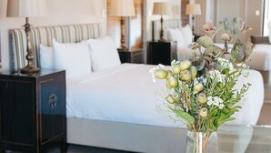 A hotel room with a bed, bedside tables, a glass coffee table, and a vase with flowers. - Banksia by the Bay (Collingwood Park)
