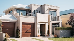 A modern two-story house with a garage, a balcony, and a well-maintained lawn. - Banksia by the Bay (Collingwood Park)