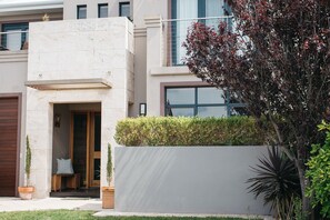 A modern building with a large entrance, a covered porch, and a well-maintained garden. - Banksia by the Bay (Collingwood Park)