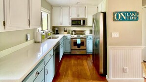 A kitchen with white cabinets, a stainless steel refrigerator, a microwave, and an oven. - Recharge Retreat and Spa Near Yosemite (Groveland)
