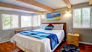 A bedroom with a large bed, wooden beams, a painting, and a nightstand. - Recharge Retreat and Spa Near Yosemite (Groveland)