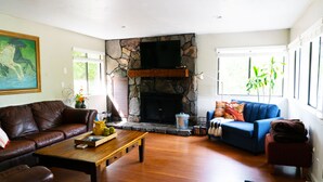 A living room with a stone fireplace, leather sofa, blue couch, and wooden coffee table. - Recharge Retreat and Spa Near Yosemite (Groveland)