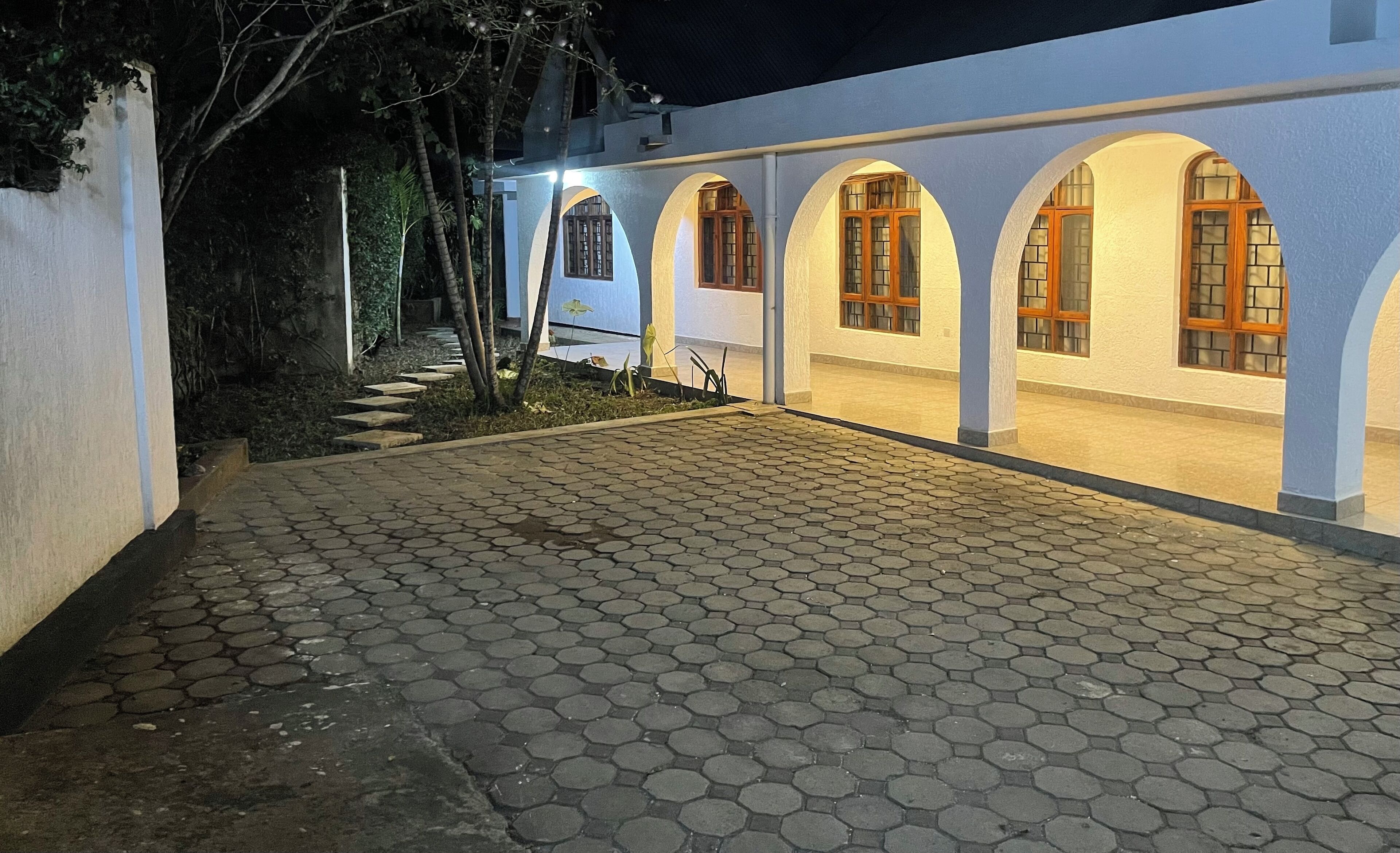 A building with a paved walkway and arched windows.
