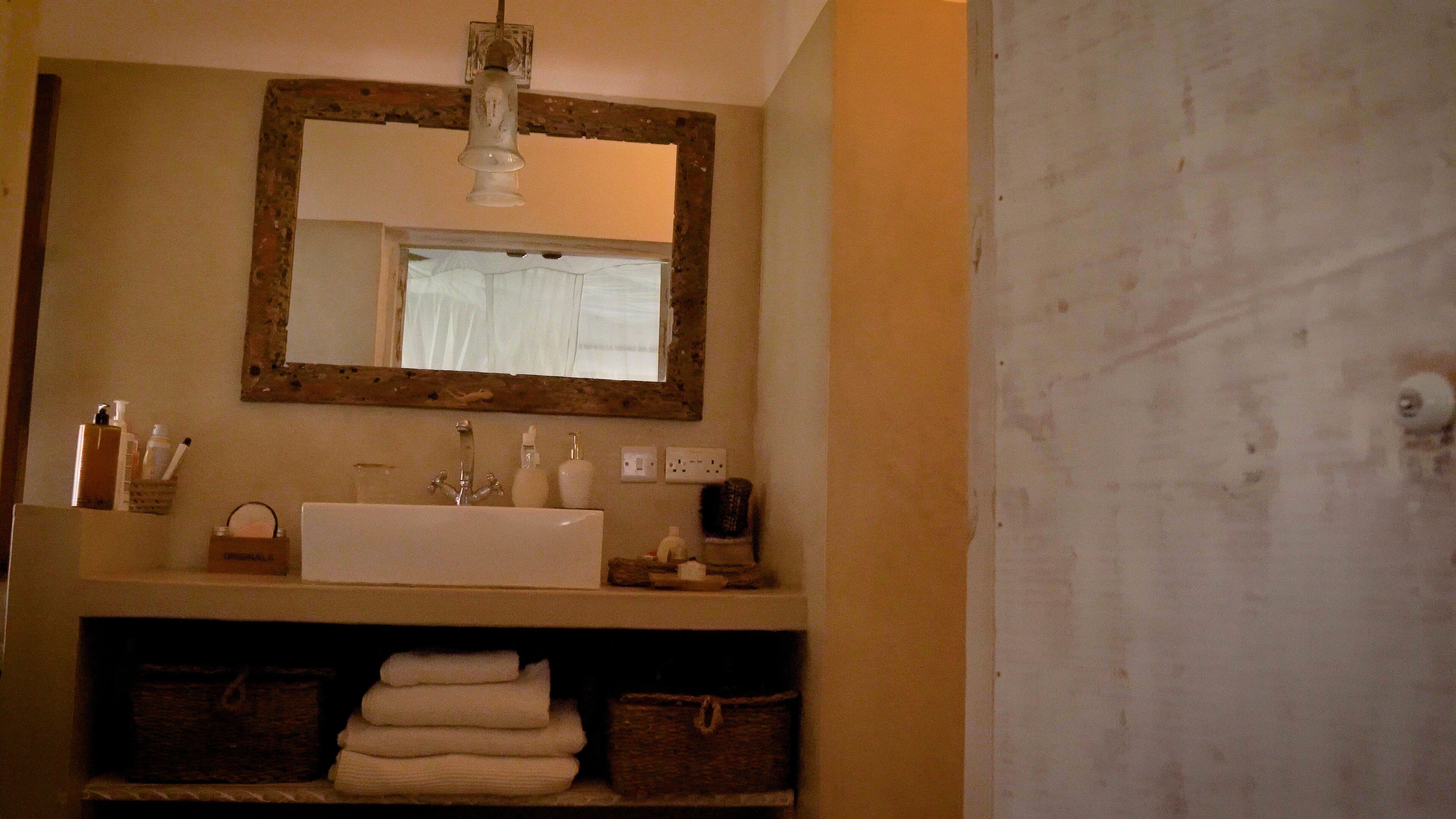 Une salle de bain avec un grand miroir, un lavabo et un porte-serviettes.