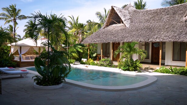 A resort with a swimming pool, thatched-roof structures, and lush tropical vegetation. - The Diamond of Africa - Luxury Villa (Malindi)