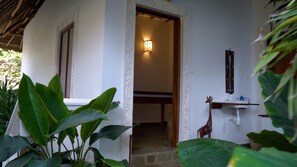 Una puerta que da a una habitación con una lámpara, una decoración de jirafa y una estantería con botellas.