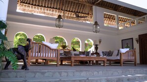 A spacious veranda with a thatched roof, wooden furniture, and a view through arched windows. - The Diamond of Africa - Luxury Villa (Malindi)