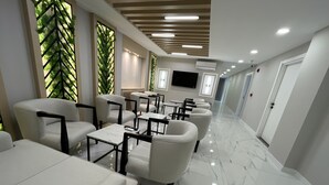 A modern hotel lobby with a long reception desk, seating area with sofas and tables, and a TV mounted on the wall. - MOF Comfort Edirne (Edirne)