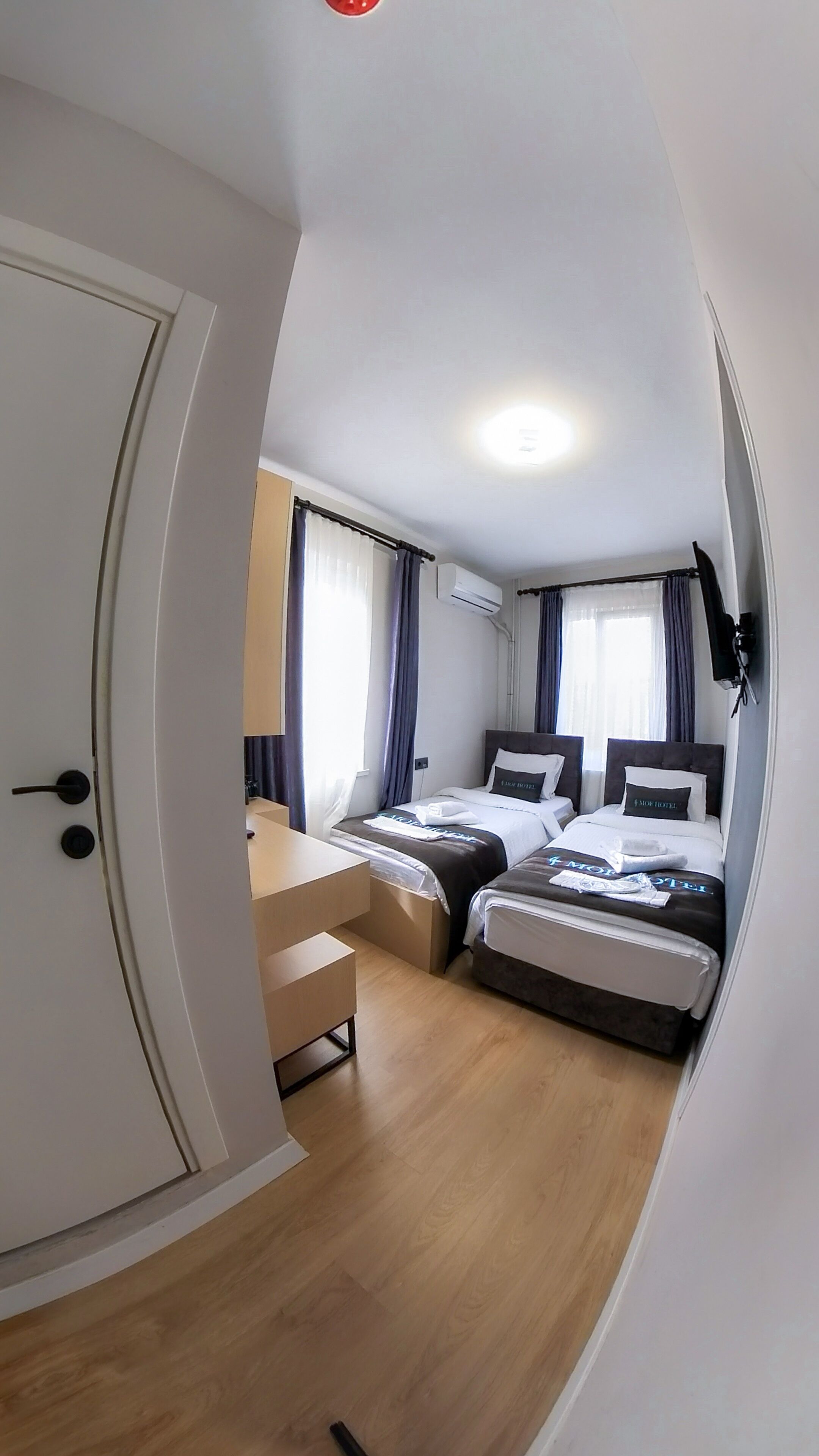A compact hotel room with two beds, a desk, and a chair.