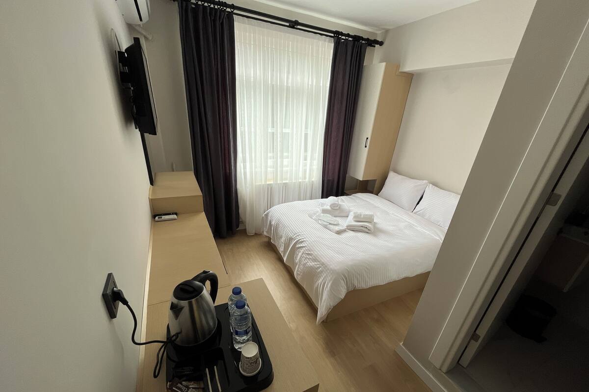 Ein Hotelzimmer mit einem Bett, einer Kaffeemaschine, einer Wasserflasche und einem Tablett mit Handtüchern.