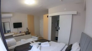 A hotel room with a large bed, a desk, a chair, a TV, and a bathroom visible through an open door. - MOF Comfort Edirne (Edirne)