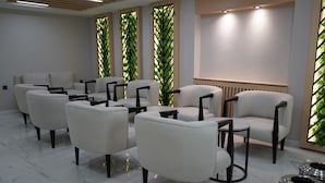 A modern waiting area with white leather chairs, a marble floor, and green vertical plant panels. - MOF Comfort Edirne (Edirne)