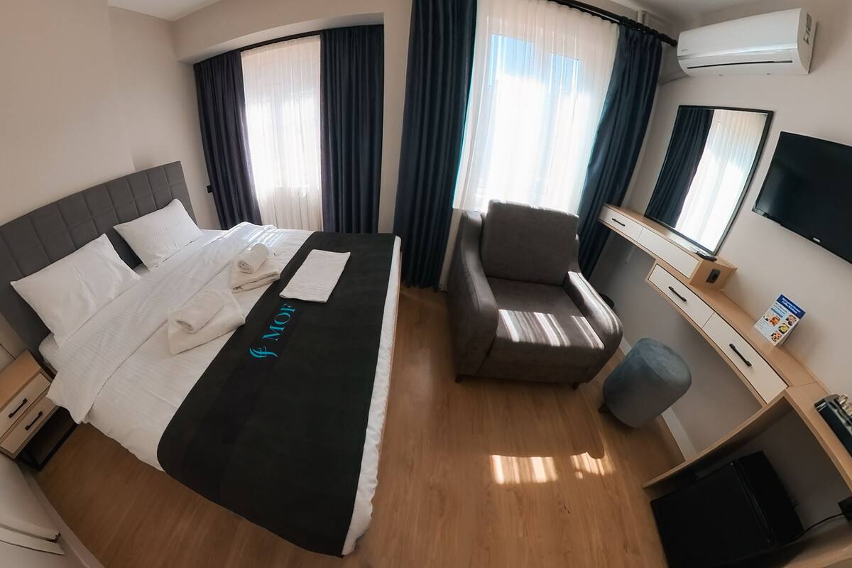 Ein Hotelzimmer mit Bett, Schreibtisch, Stuhl und Fernseher.