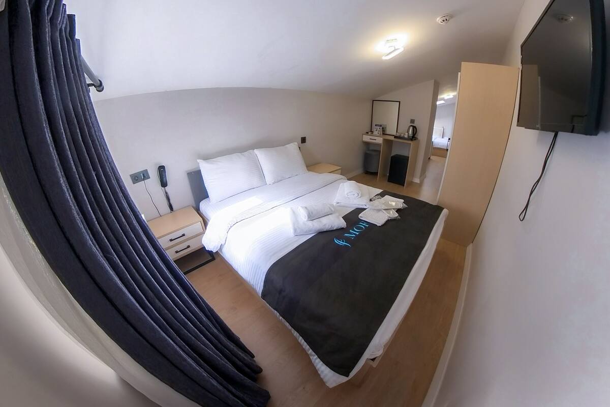 Ein Hotelzimmer mit Bett, Nachttisch, Telefon, Spiegel und Fernseher.