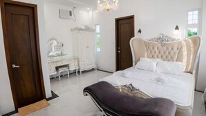 A bedroom with a large bed, a dresser, a vanity, and a chandelier. - Mancion Bakasyunan Resort San Pablo (San Pablo)