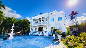 A white colonial-style building with a central courtyard, multiple balconies, and a fountain. - Mancion Bakasyunan Resort San Pablo (San Pablo)