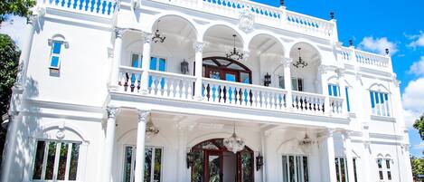 A white building with a balcony, columns, and a staircase.