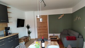 A modern living space with a dining area, kitchen, and seating area. - Ferienwohnung 40m² mit Terrasse, bis 3 Personen, Separates Schlafzimmer (Grassau)