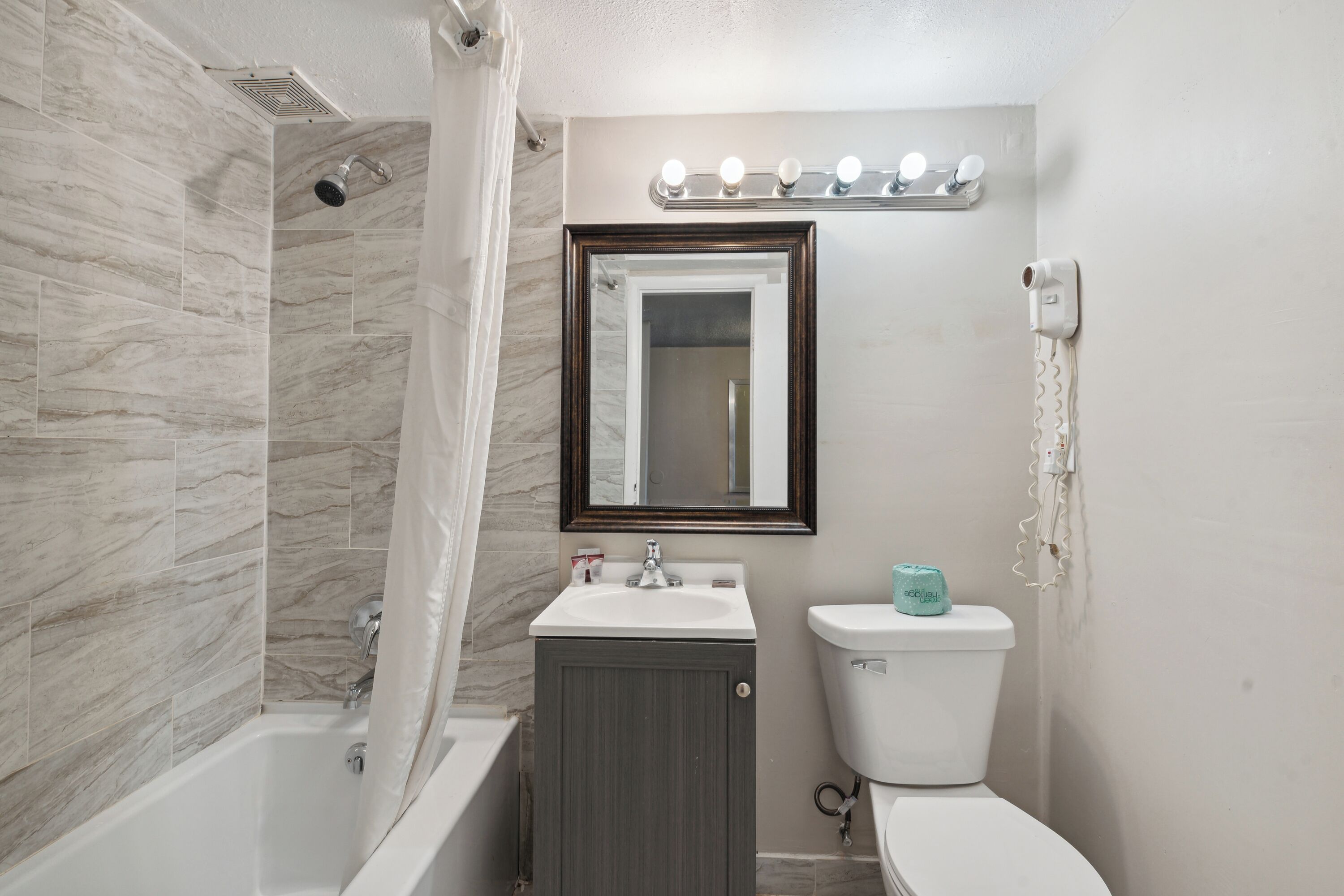 Un bagno con vasca, lavandino, WC e uno specchio con illuminazione soprastante.
