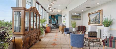 A spacious lobby with a grand wooden cabinet, comfortable seating, and potted plants.
