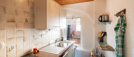 A compact kitchen with a wooden countertop, a sink, and a window.