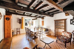 A dining area with a wooden table and chairs, a sofa, and a bookshelf. - Casa Merlot in Caslano for 4 (Caslano)