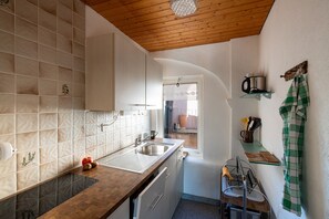 A kitchen with a wooden ceiling, a sink, a window, and a shelf with kitchen utensils. - Casa Merlot in Caslano for 4 (Caslano)
