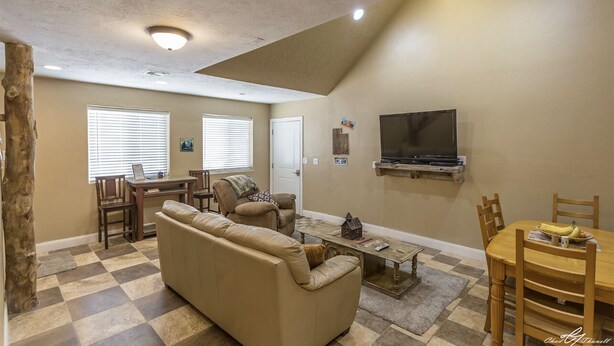 A living room with a sofa, dining table, and chairs, a TV mounted on the wall, and a fireplace.