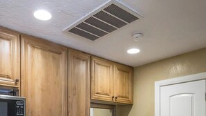 A kitchen with wooden cabinets, a stainless steel dishwasher, a microwave, a sink, and a white door.
