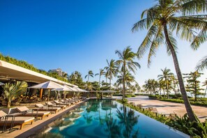 A poolside area with lounge chairs and umbrellas, surrounded by palm trees and a clear sky. - 3 Bedrooms private pool villa Phu Quoc (Phu Quoc)