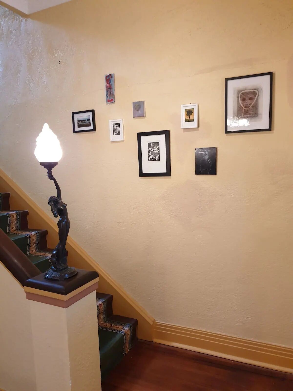 A staircase with a wall-mounted light fixture and framed artwork.