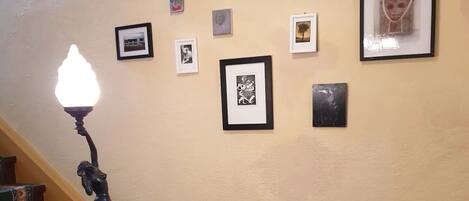 A staircase with a wall-mounted light fixture and framed artwork.