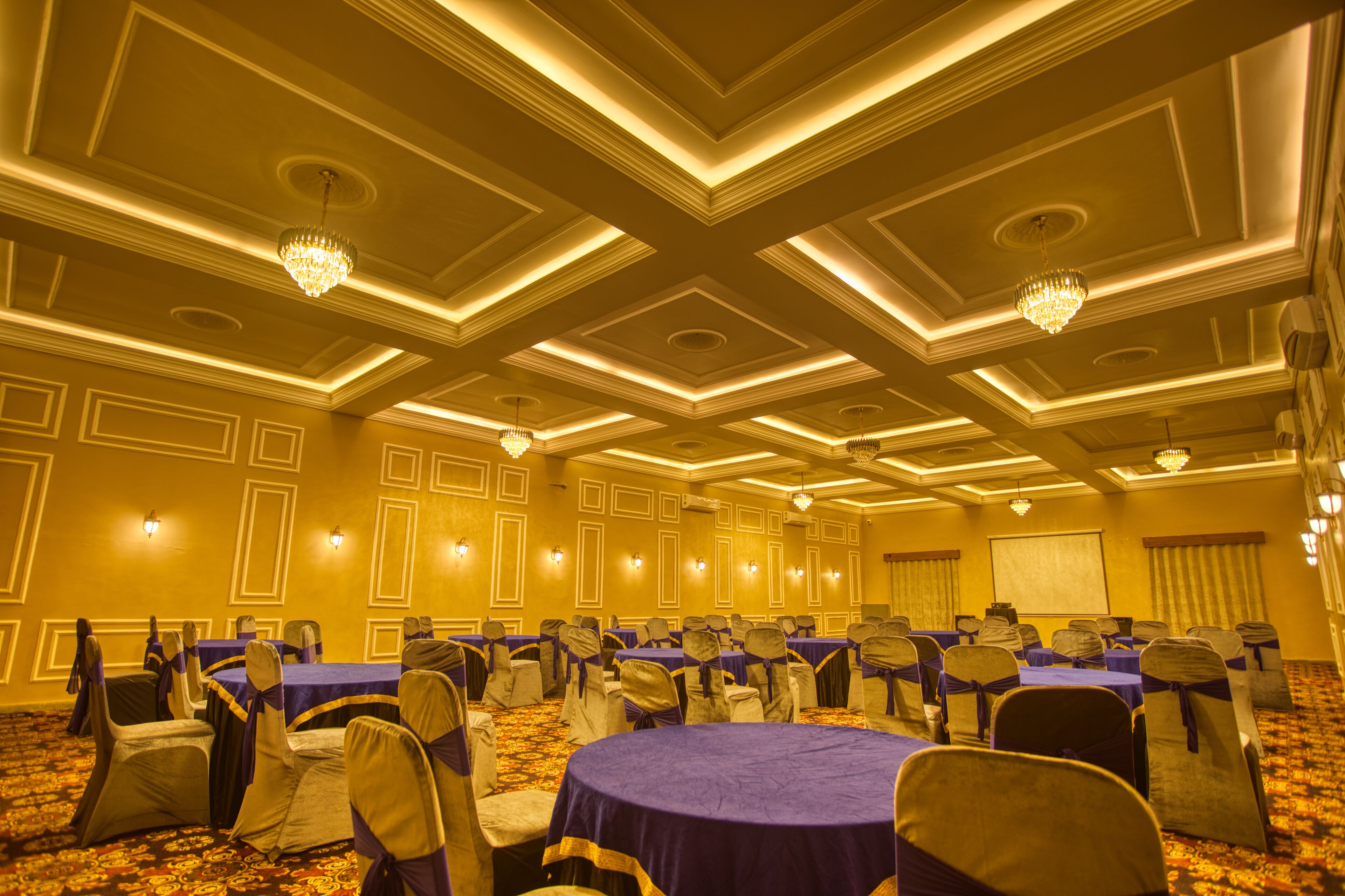 A conference room with multiple tables and chairs, arranged in rows.