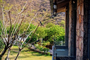 Ein Gebäude mit Naturstein-Fassade und Blick auf einen angelegten Garten mit Baum und Zaun.