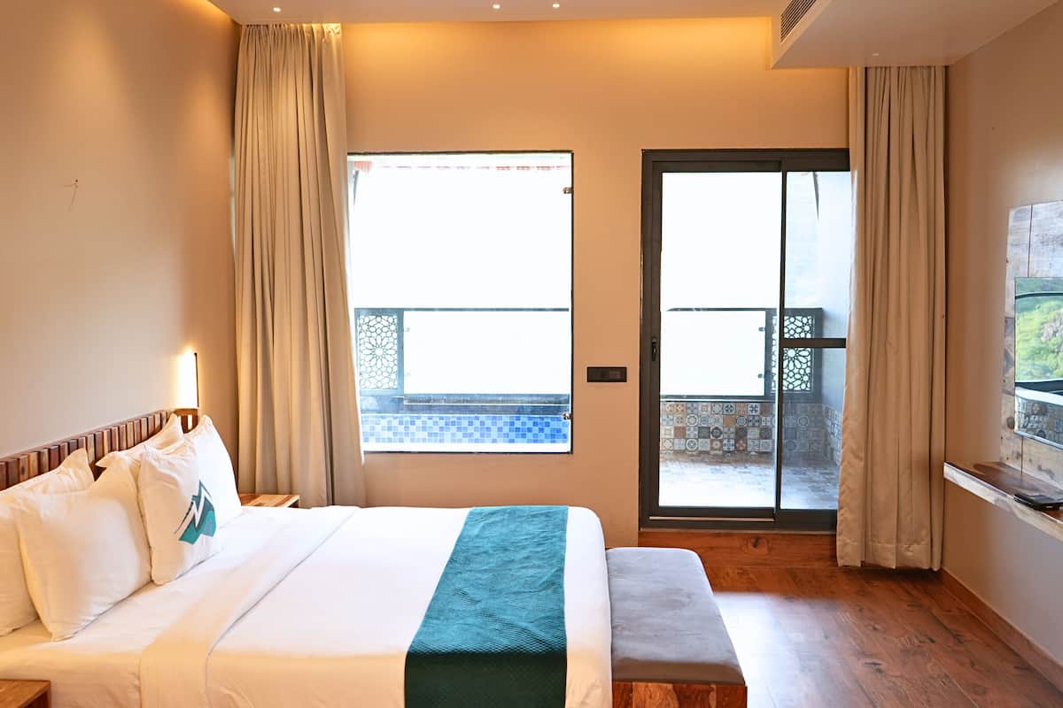 A hotel room with a bed, a TV, a balcony, and a view of the outdoors.