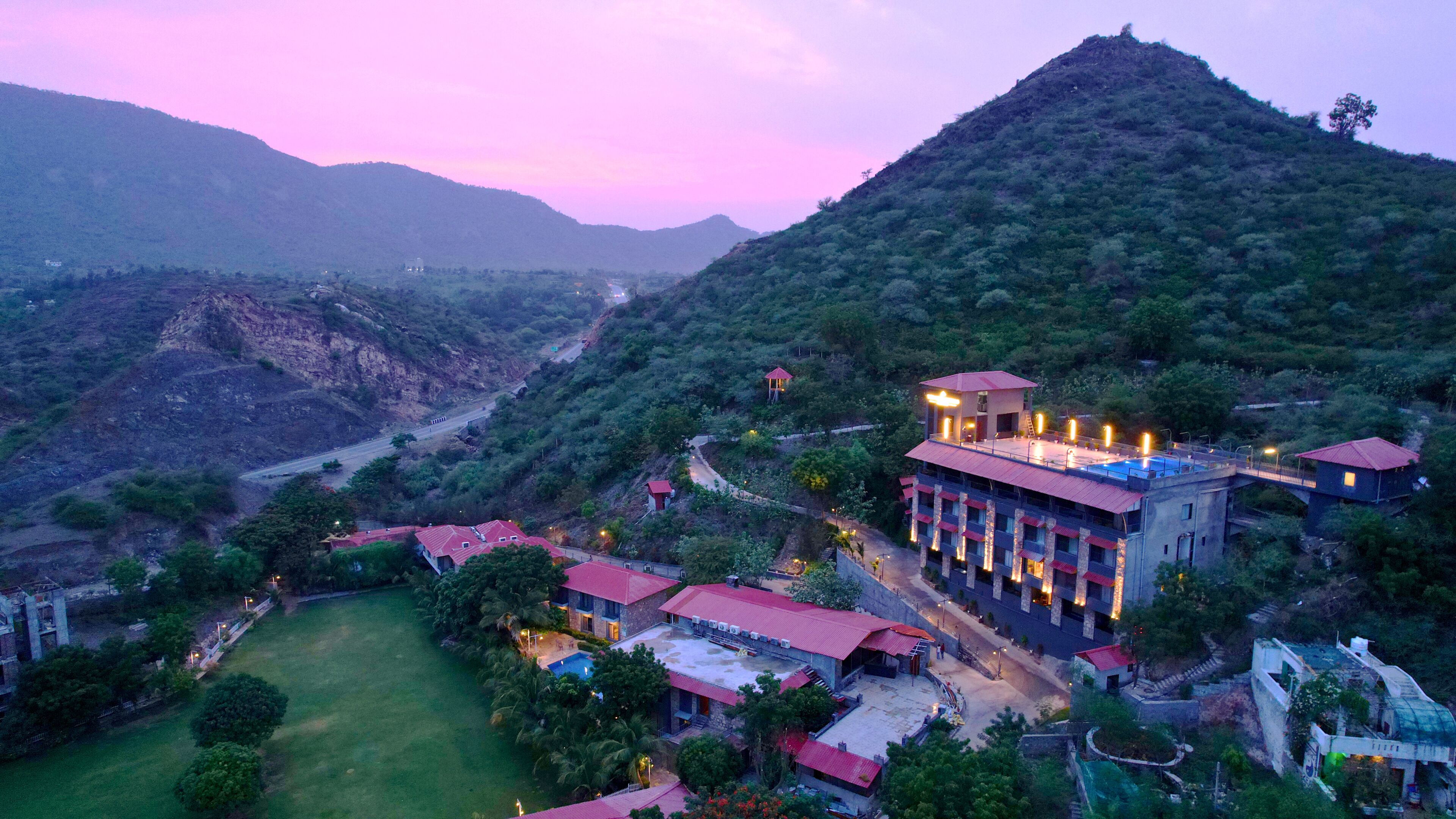 A hotel with multiple buildings, a swimming pool, and a mountainous backdrop.