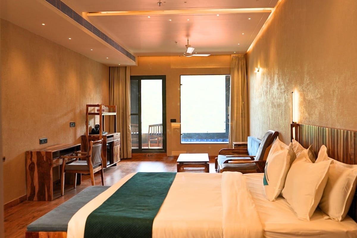 A hotel room with a bed, desk, chair, and a view of the outside.