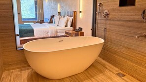 Luxe kamer | Badkamer | Een douche, pantoffels, handdoeken, shampoo