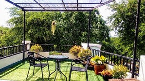 A covered balcony with a glass roof, surrounded by lush greenery. - Sea Star House (Krabi)